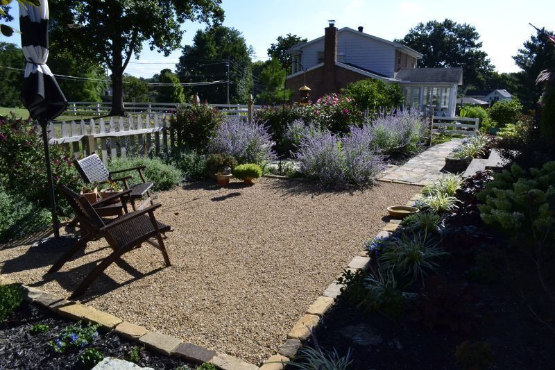 Gravel garden path with lavender, benches, and a house in the background