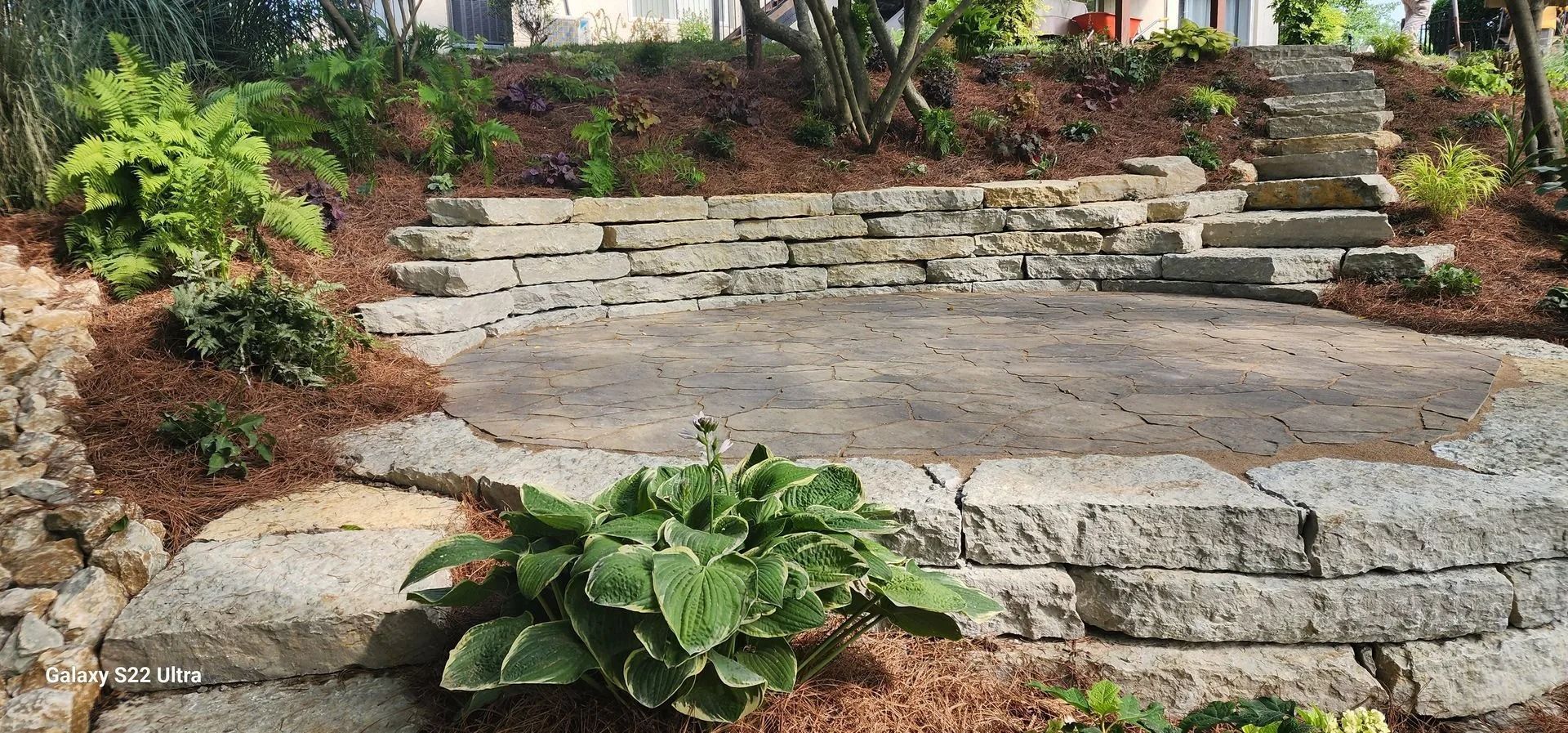 Stone garden steps with a cracked walkway, bordered by plants and mulch