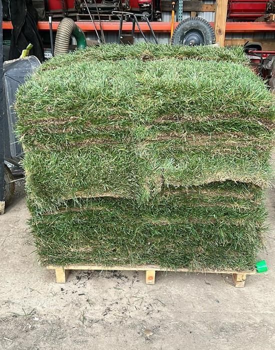 Stacked sod rolls on a pallet in a warehouse yard