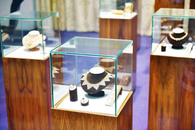 Jewelry displays in glass cases on wooden stands, including a black-and-white necklace and ring on a purple carpet.