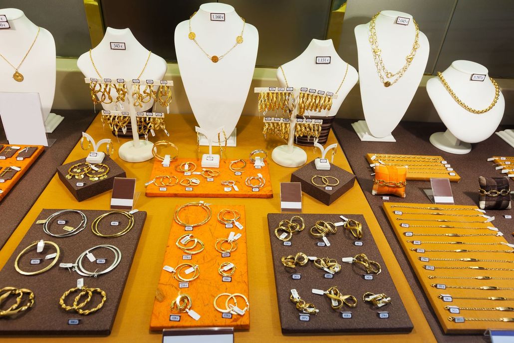 Jewelry display with necklaces, bracelets, rings, and earrings arranged on white busts and trays