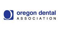 Logo for the Oregon Dental Association, featuring a blue square with a stylized white crescent and text below.