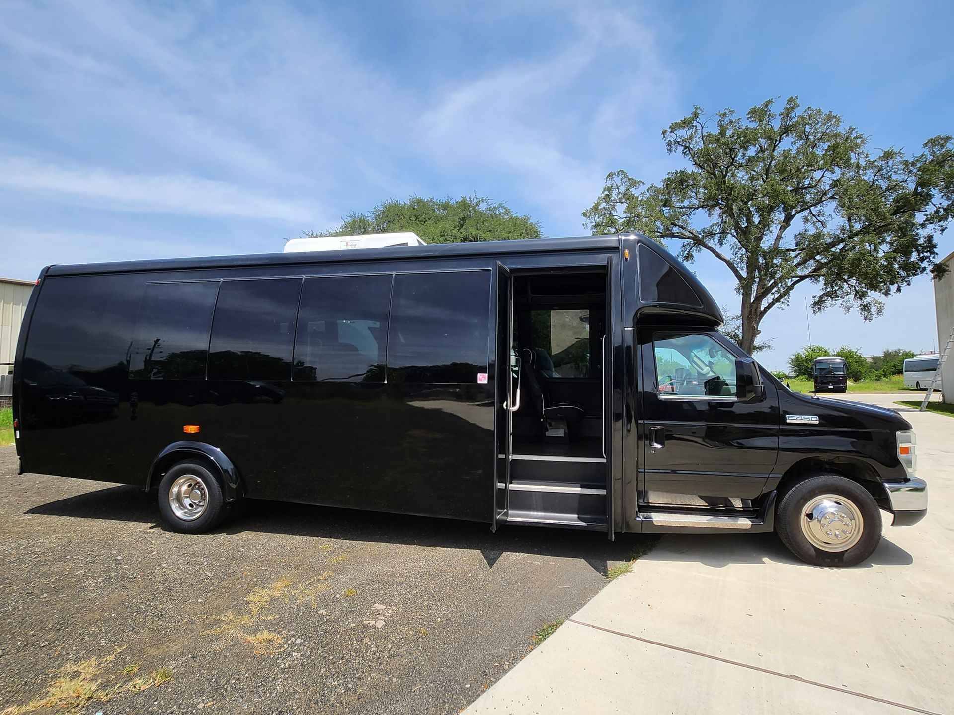 Black passenger bus with open door parked outdoors on a sunny day