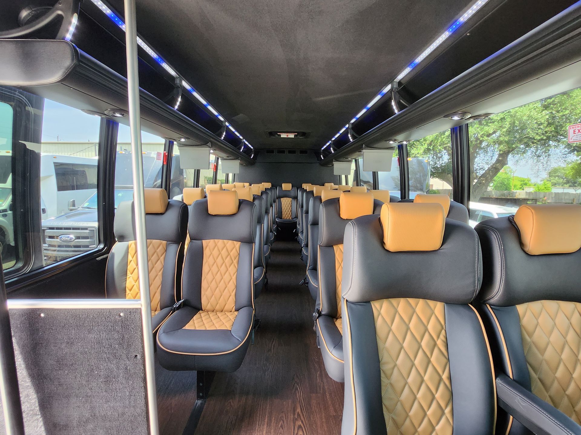 Interior view of a passenger bus with rows of black and tan quilted seats