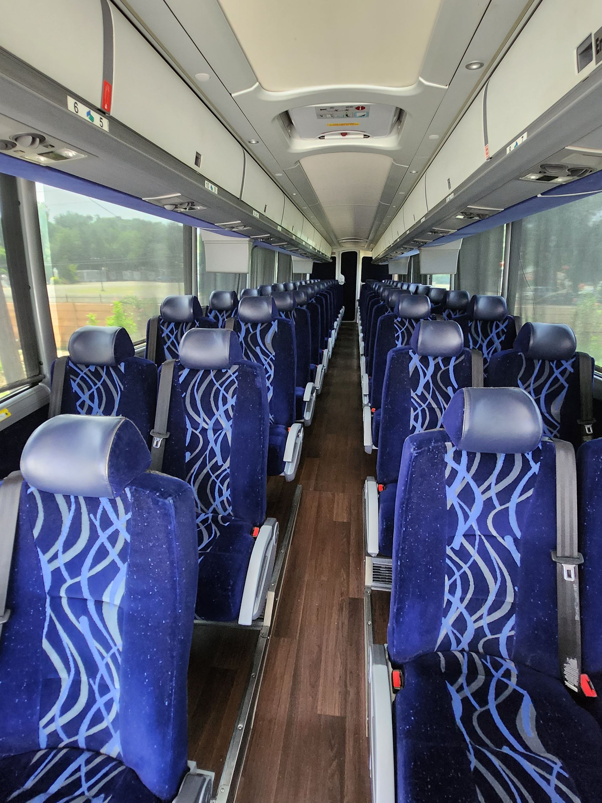Interior of a coach bus with rows of blue patterned seats and overhead compartments