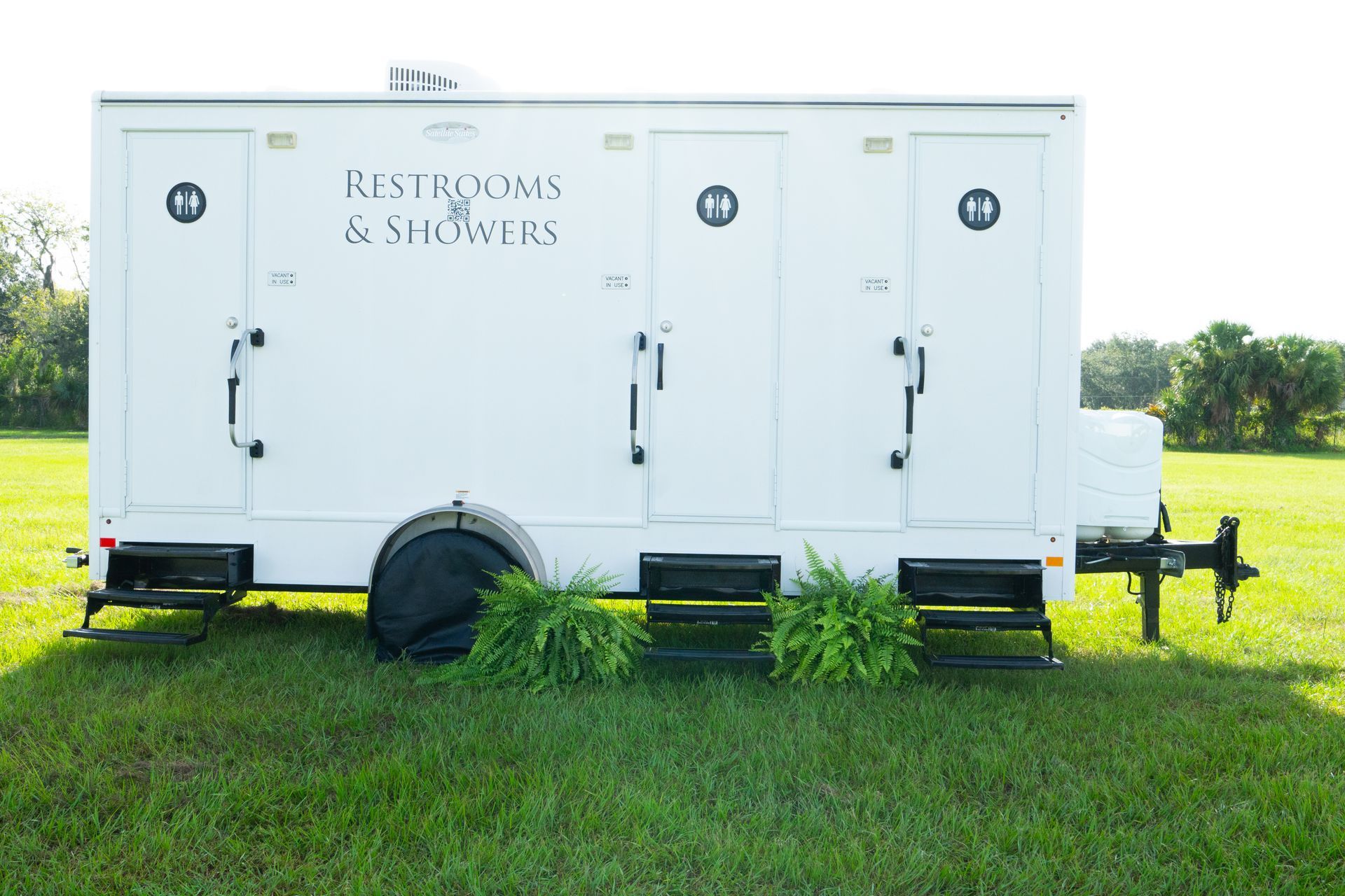 A white trailer is parked in a grassy field.