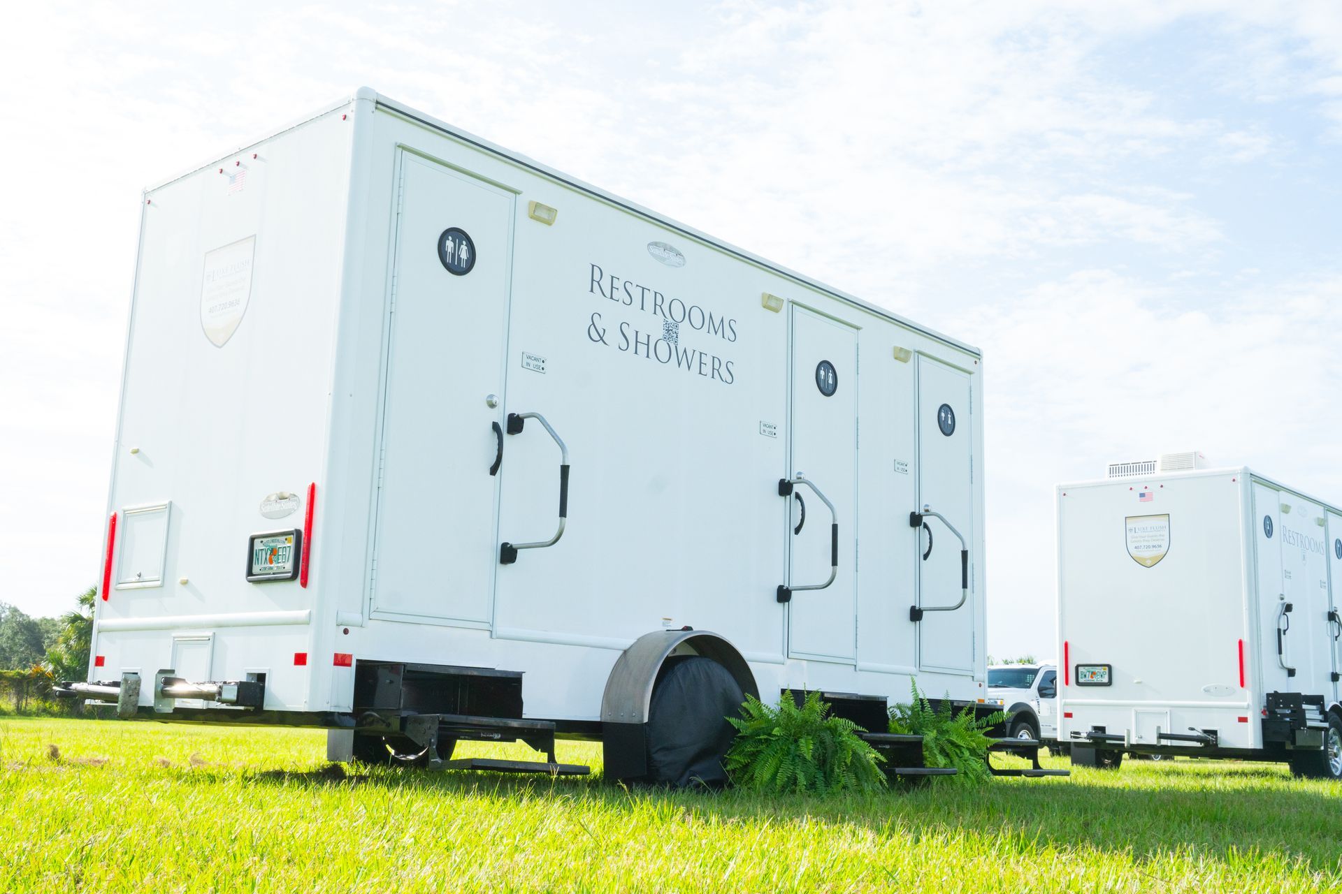 White portable restroom trailers on a grassy field.