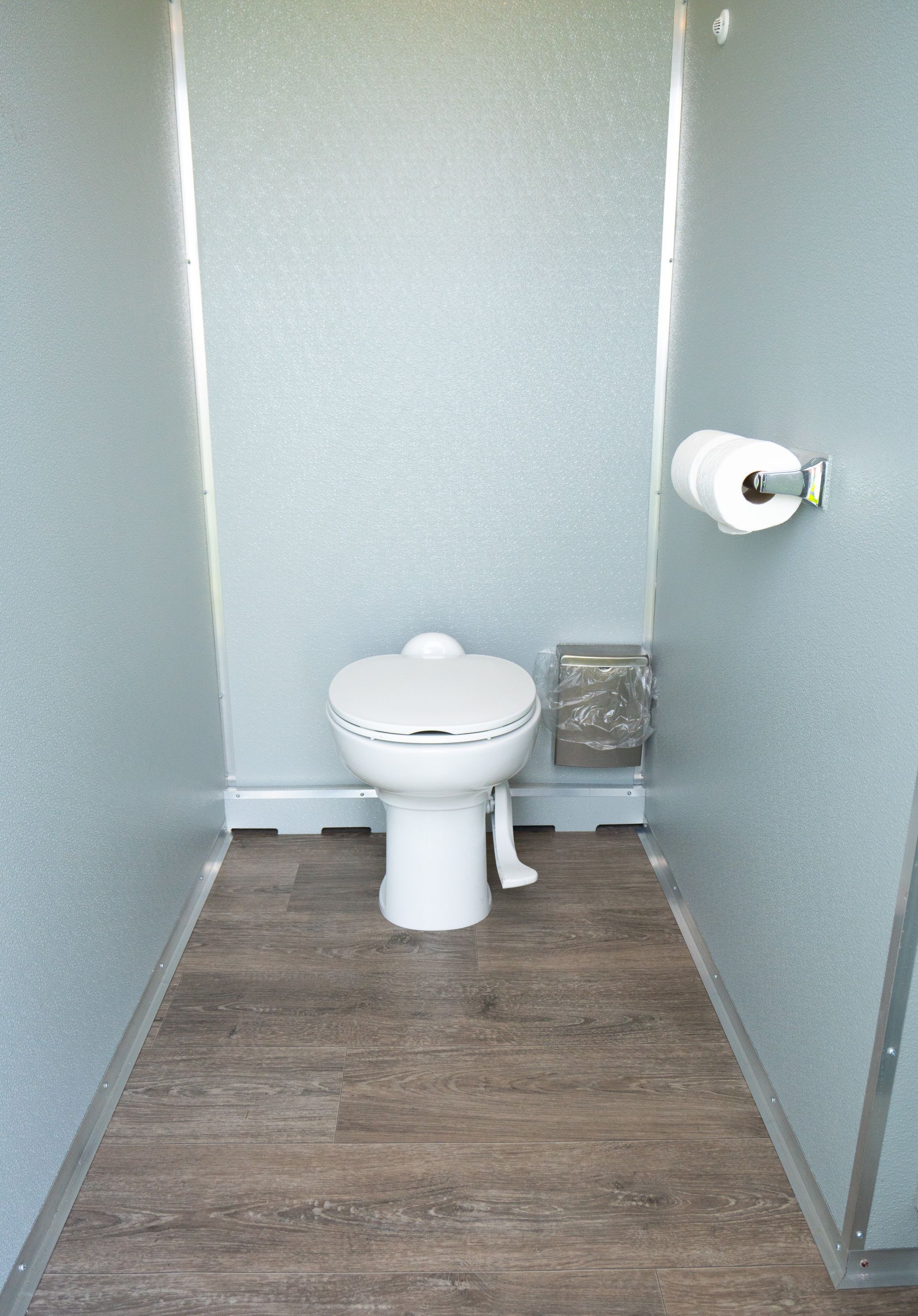 A toilet is sitting in a bathroom next to a paper towel dispenser.
