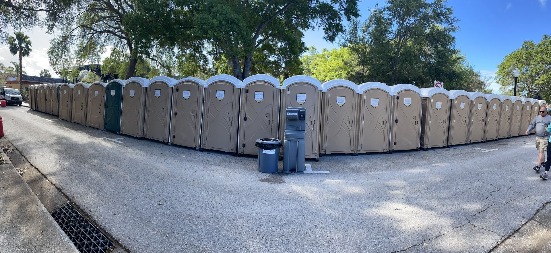 A row of portable toilets are lined up in a parking lot.