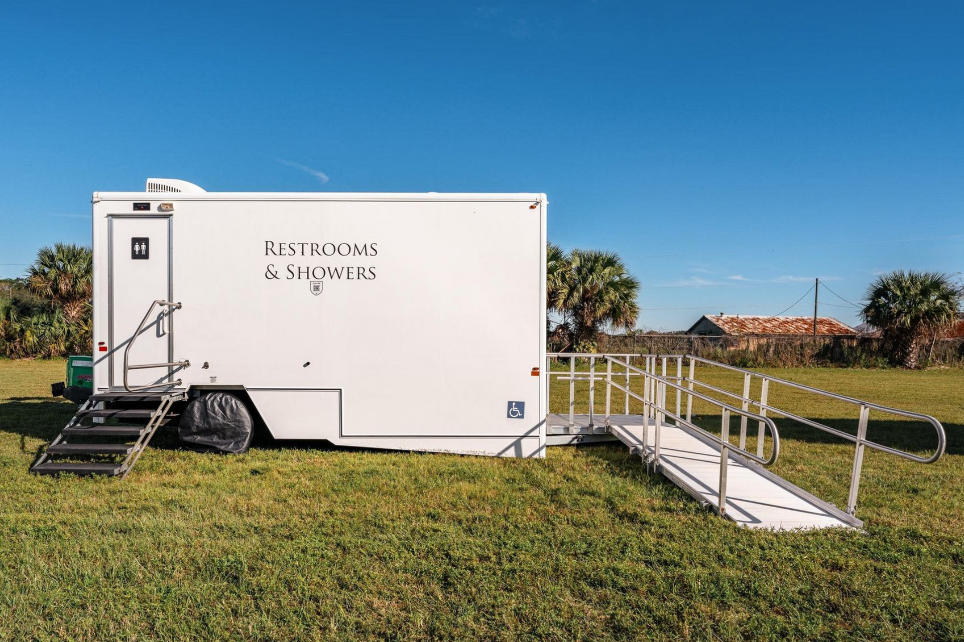 White portable restroom trailers on a grassy field. 
