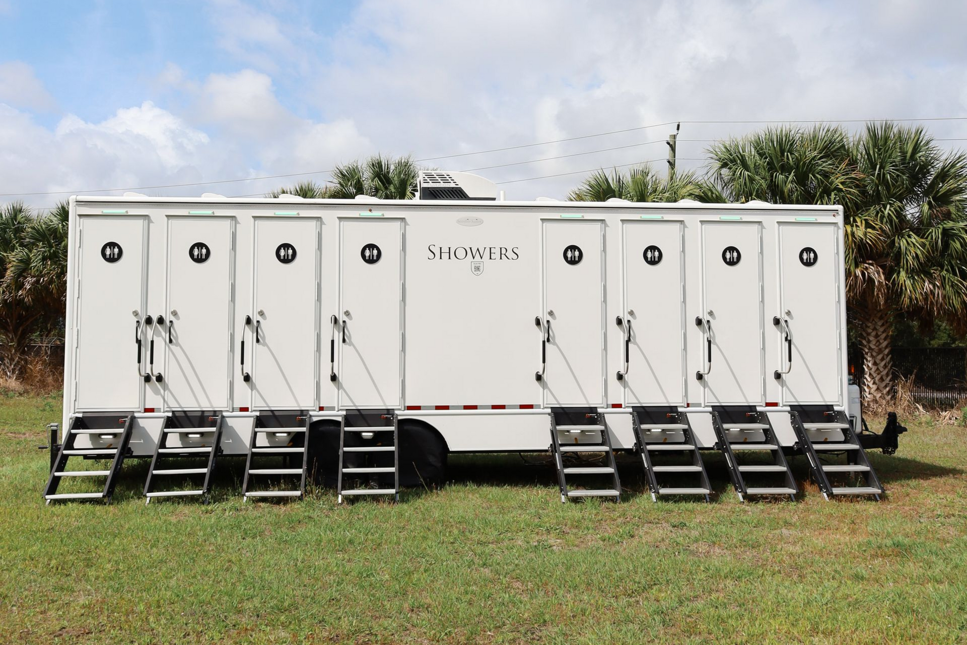 A white trailer is parked in a grassy field.