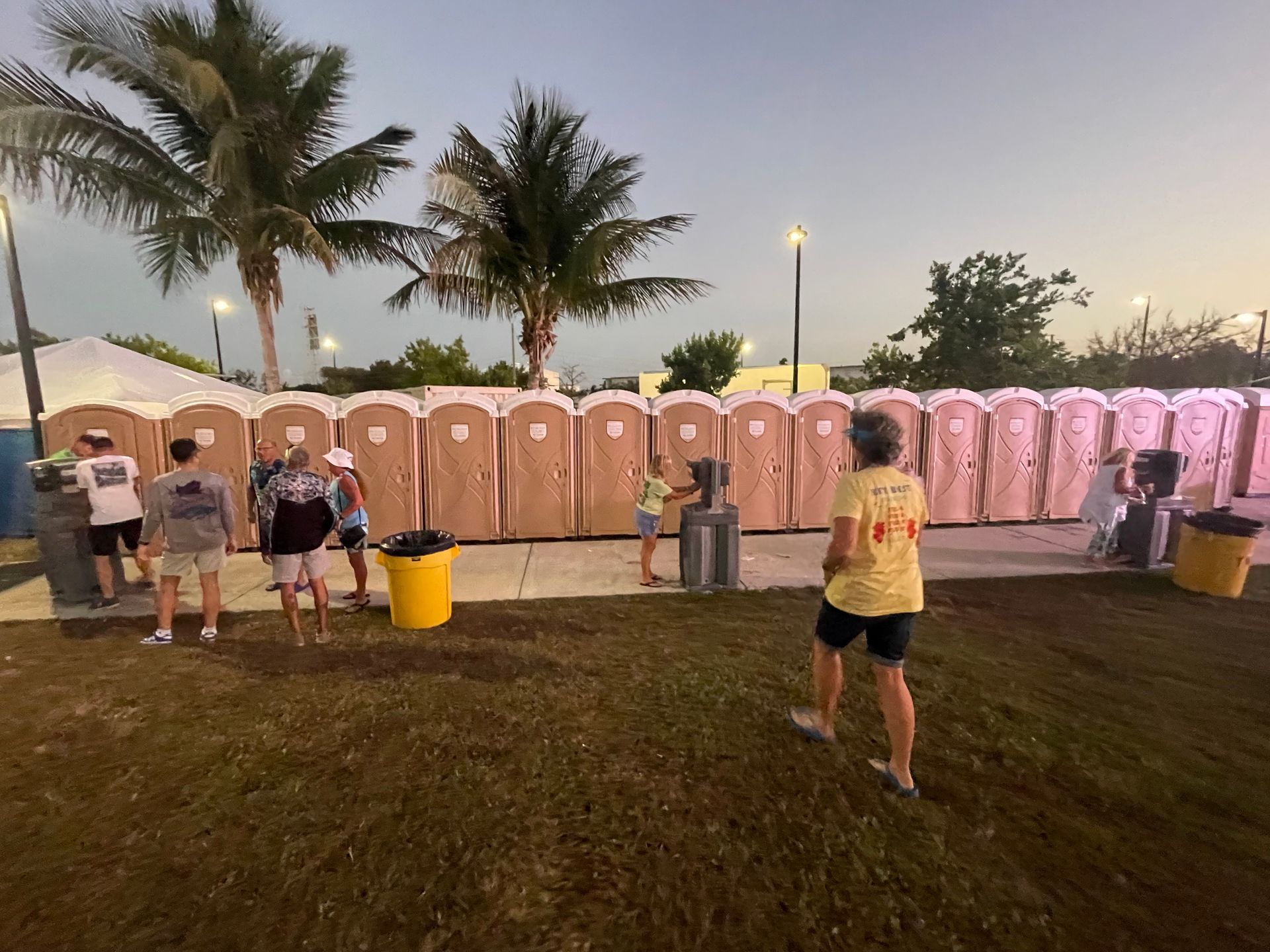 A group of people are standing in front of a row of portable toilets.