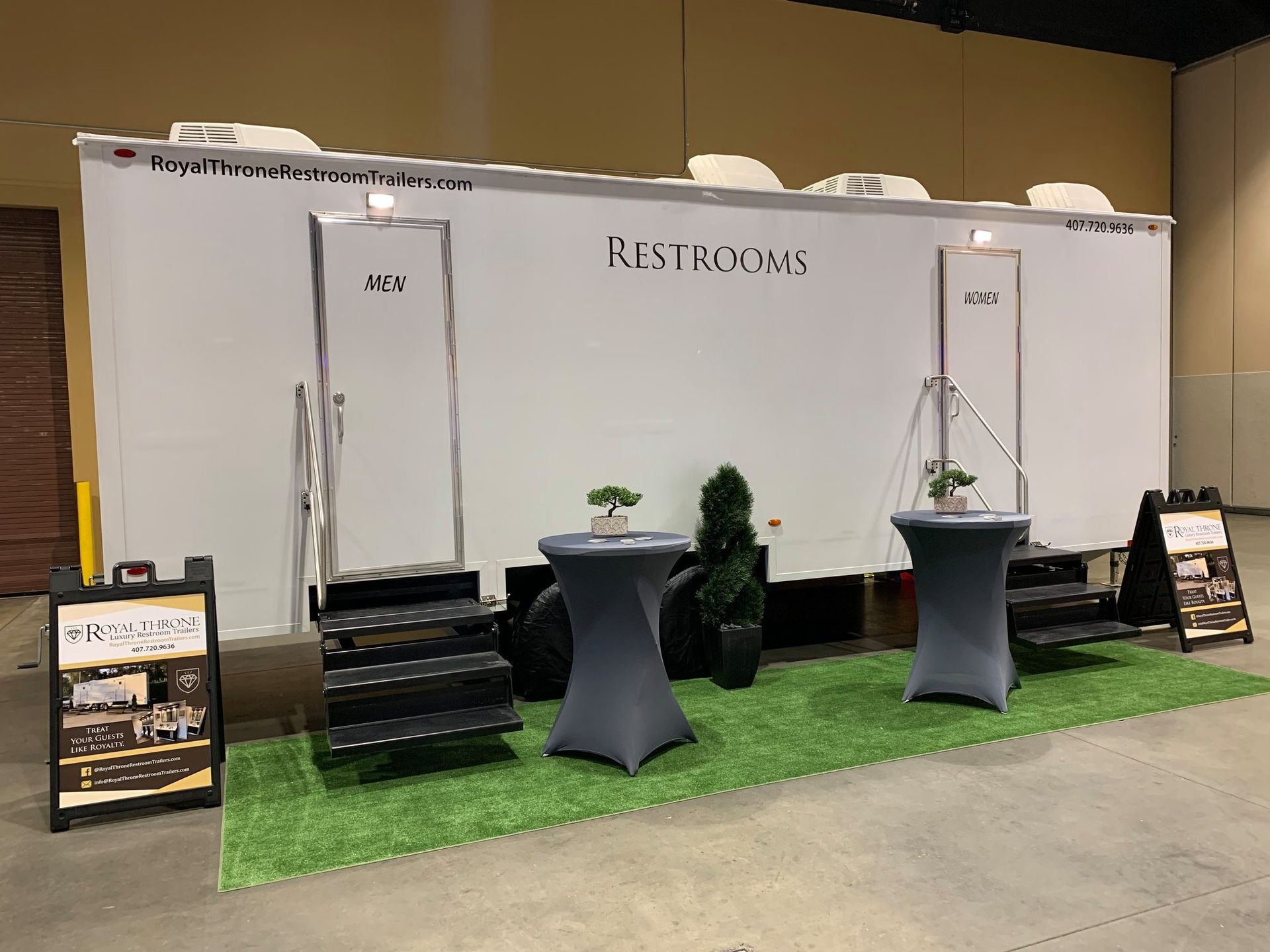 A white trailer with tables and stairs in front of it