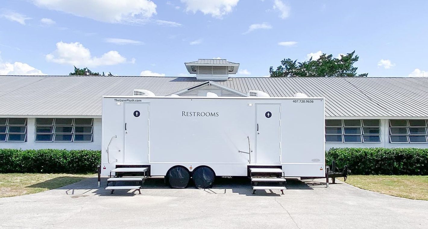 A white trailer is parked in front of a building