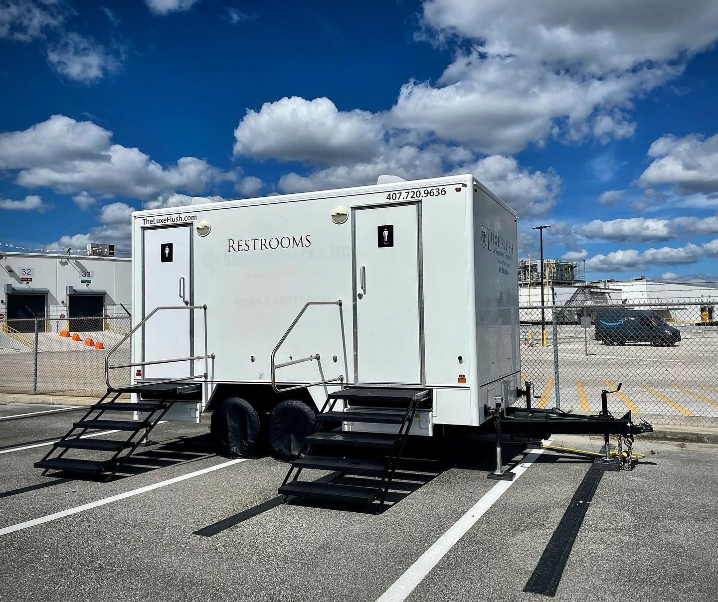 A white trailer with stairs attached to it is parked in a parking lot