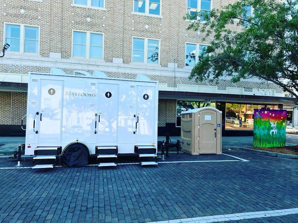 Two portable toilets are parked in front of a building