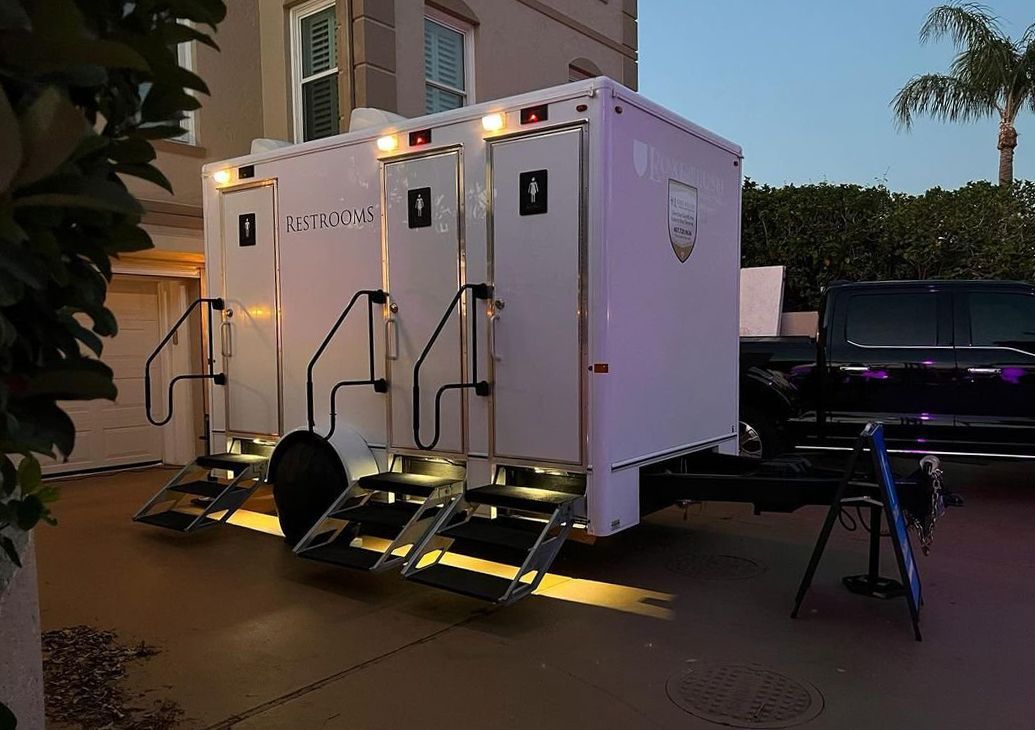 A trailer with two toilets on it is parked in front of a building