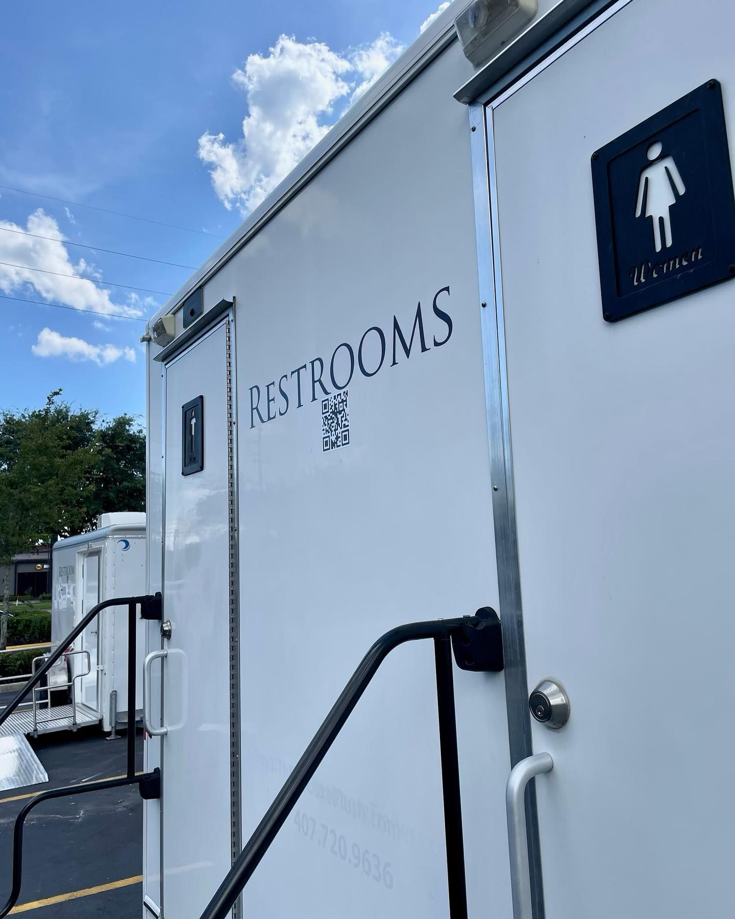 A white trailer with a sign on the door that says restrooms