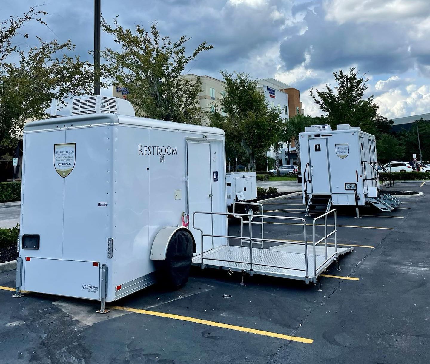 Three white trailers are parked in a parking lot
