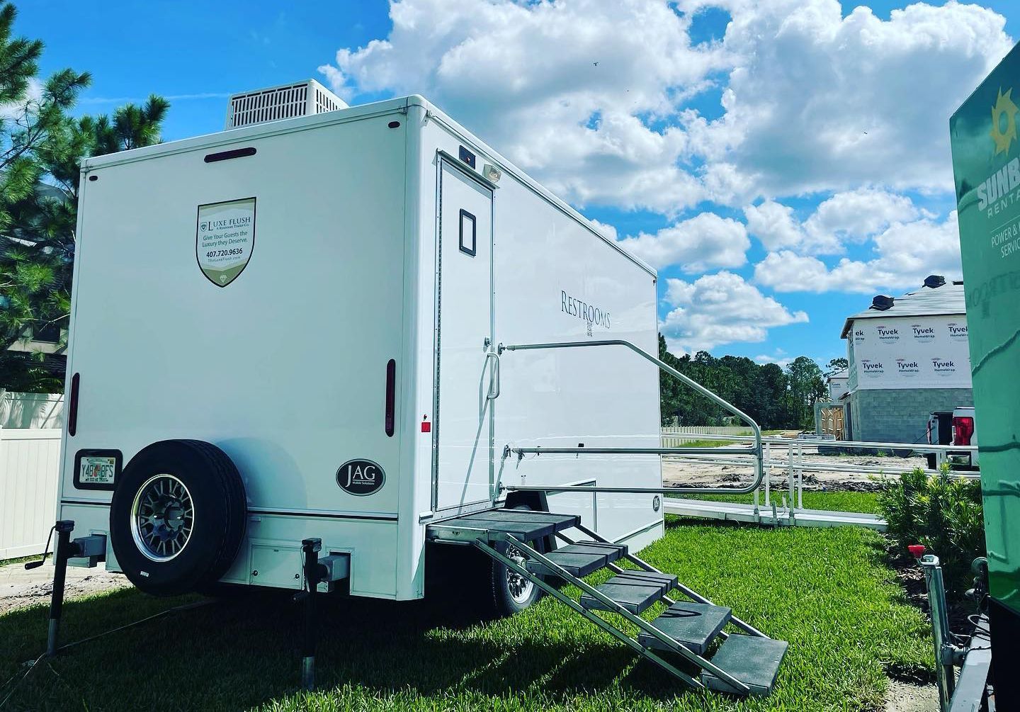 A white trailer with stairs attached to it is parked in the grass