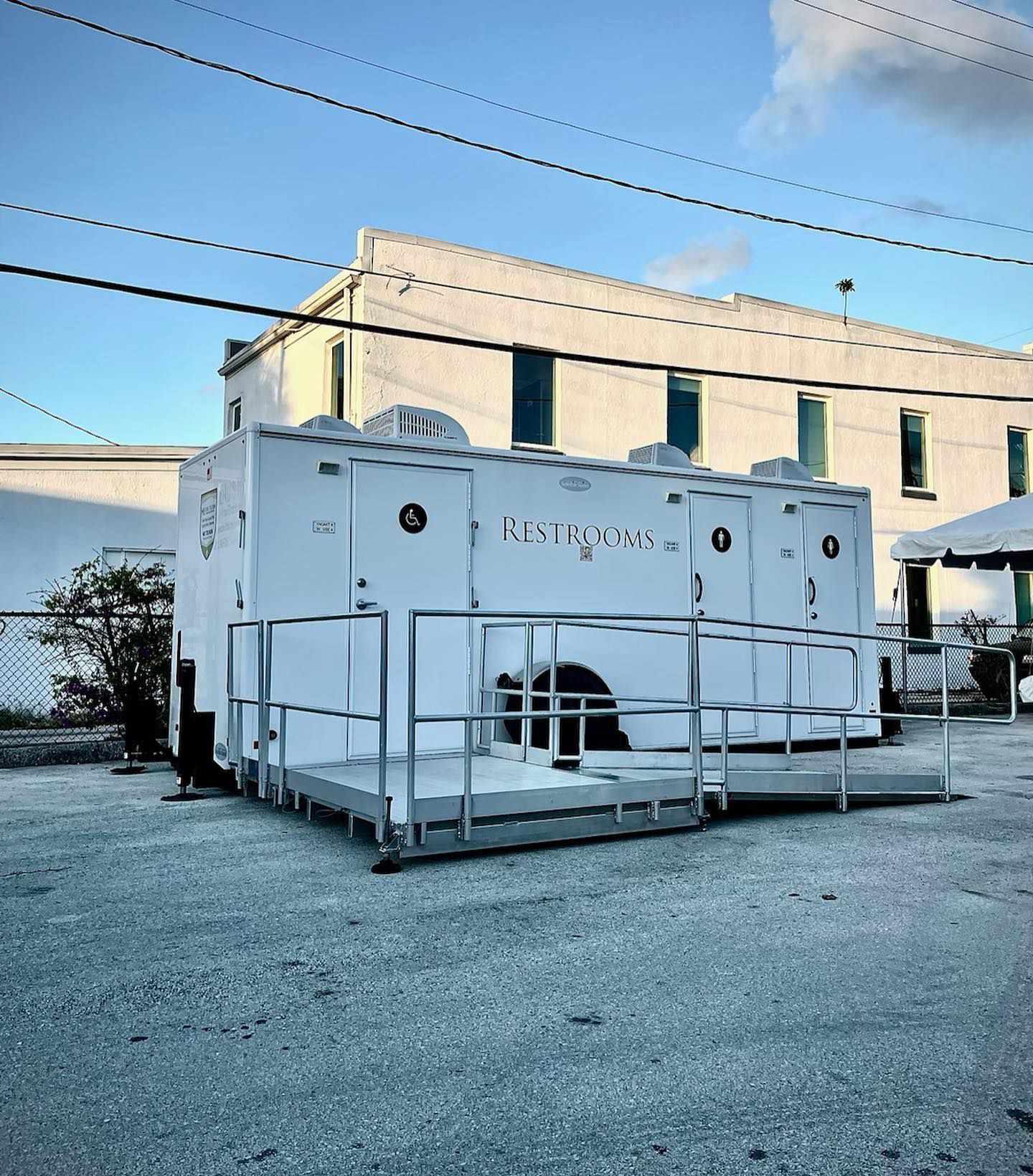 A white trailer with a ramp is parked in front of a building