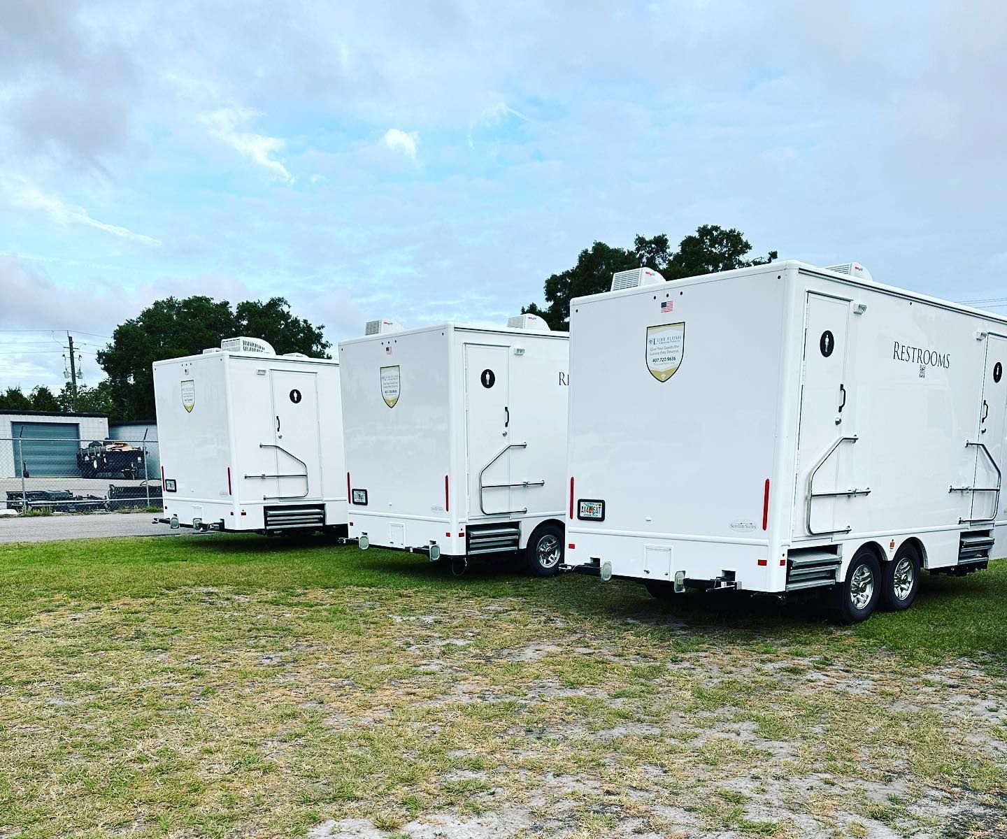 Three white trailers are parked in a grassy field