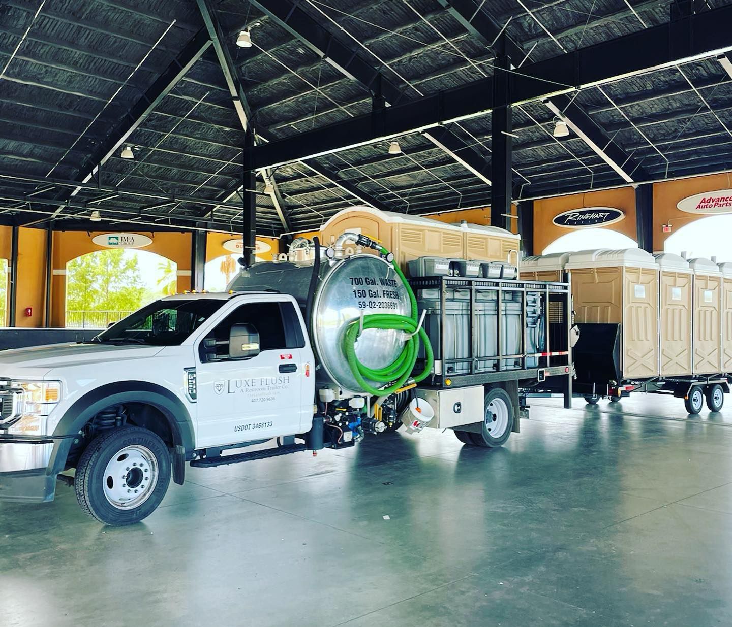 White truck with portable toilets, under a covered structure.