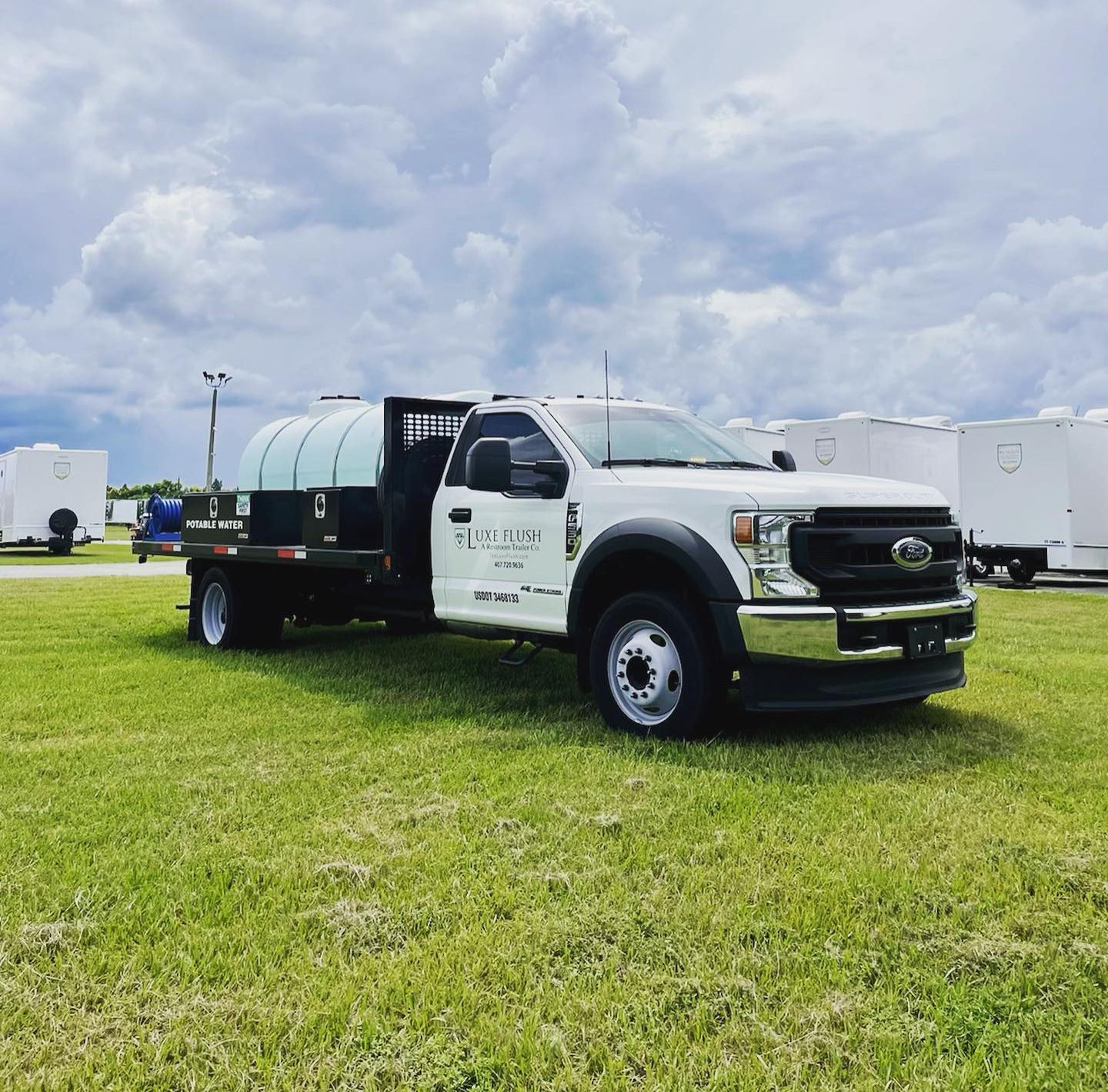 A white truck is parked in a grassy field