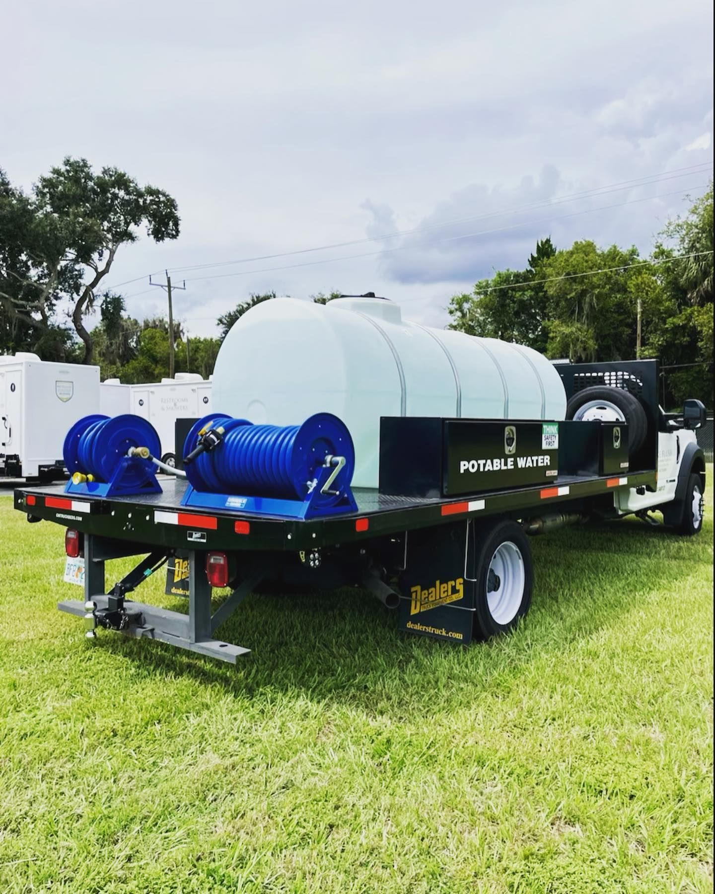 A truck with a trailer attached to it is parked in a grassy field