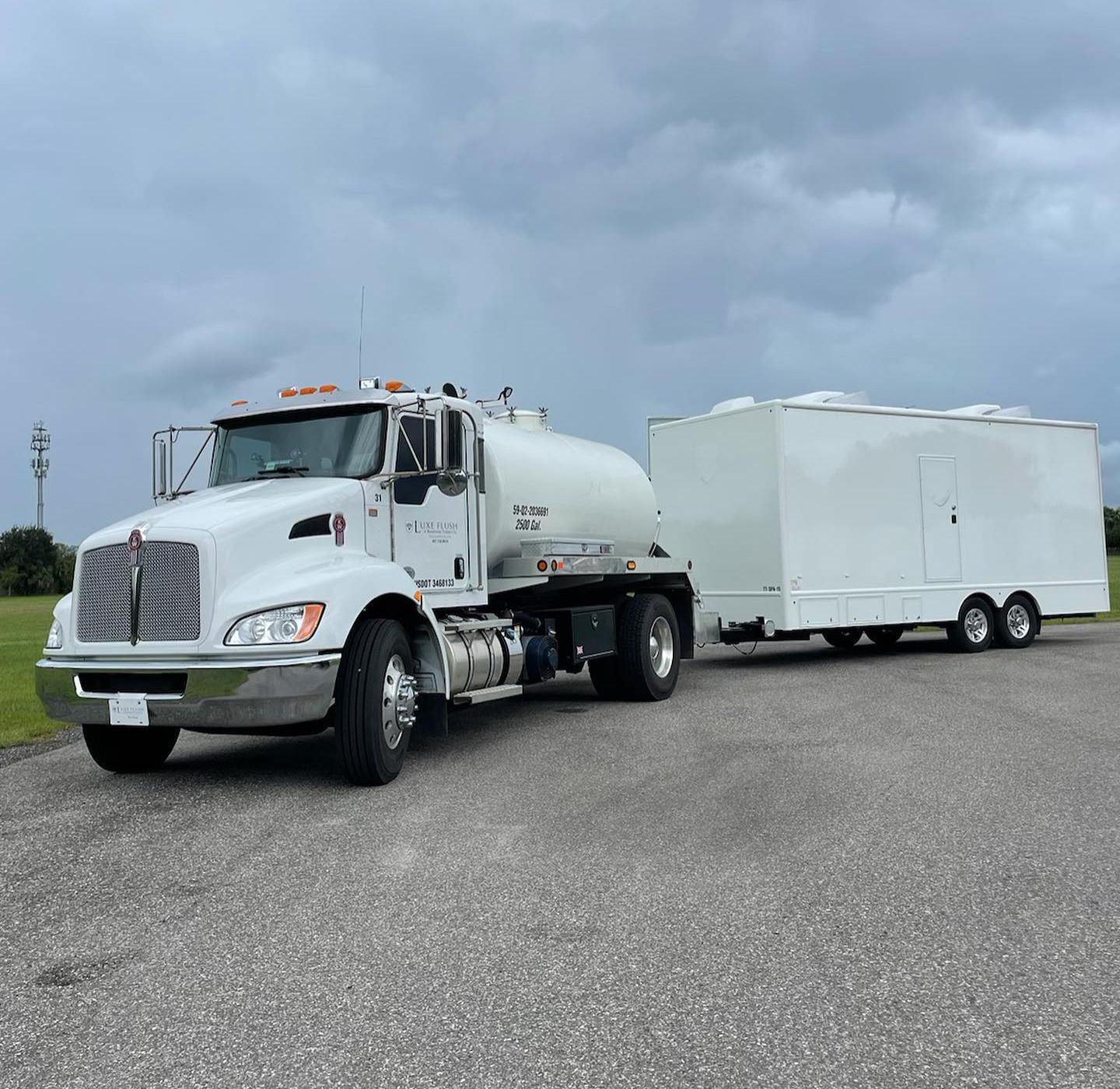 A white truck with a trailer attached to it is parked on the side of the road
