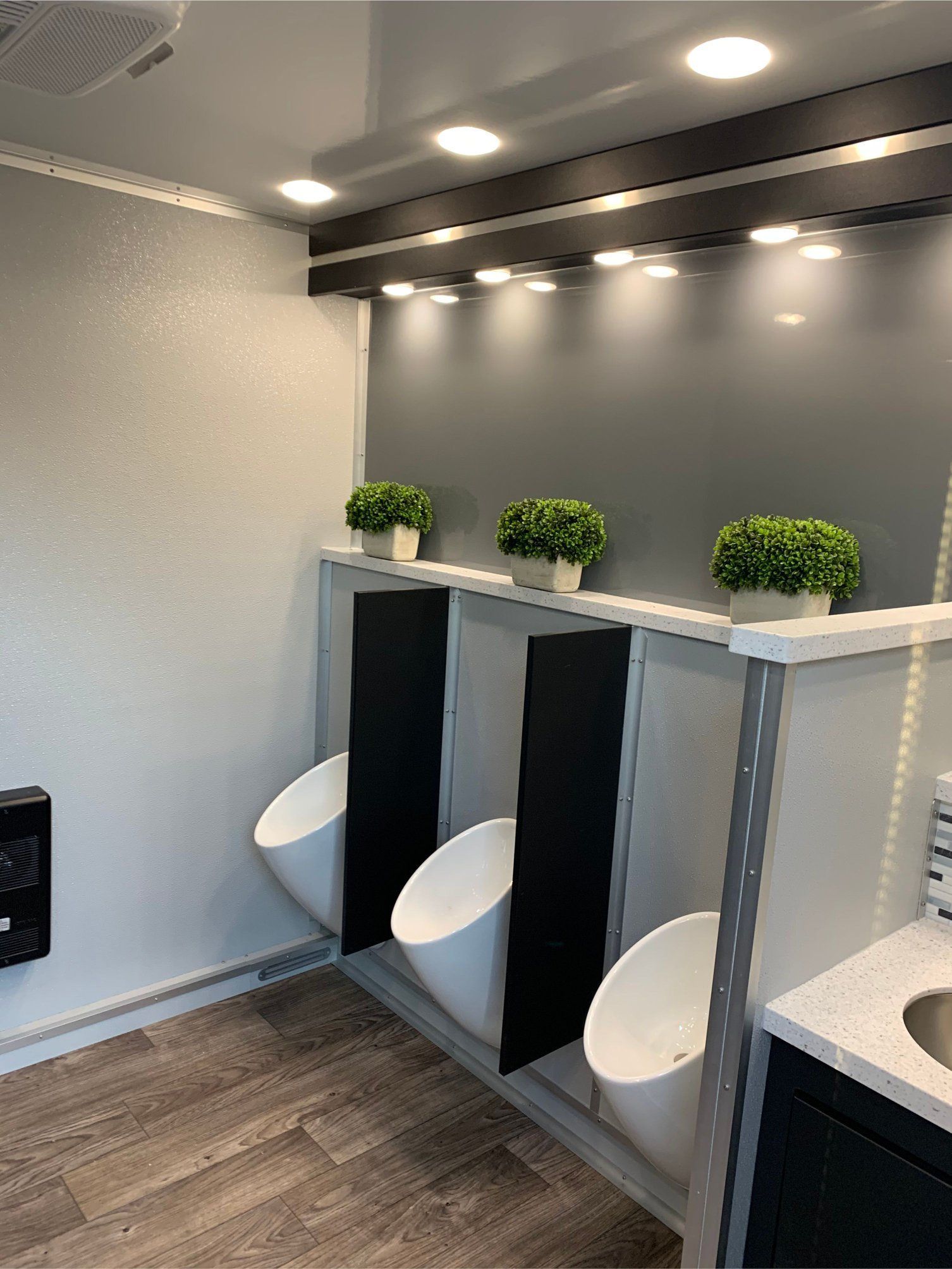 A bathroom with three urinals and a sink