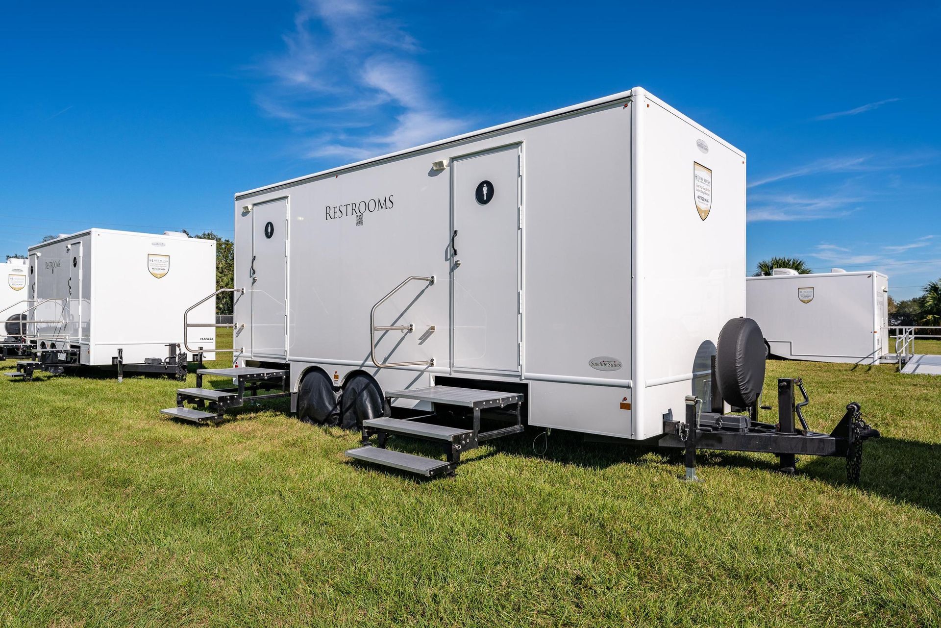 A row of white trailers are parked in a grassy field