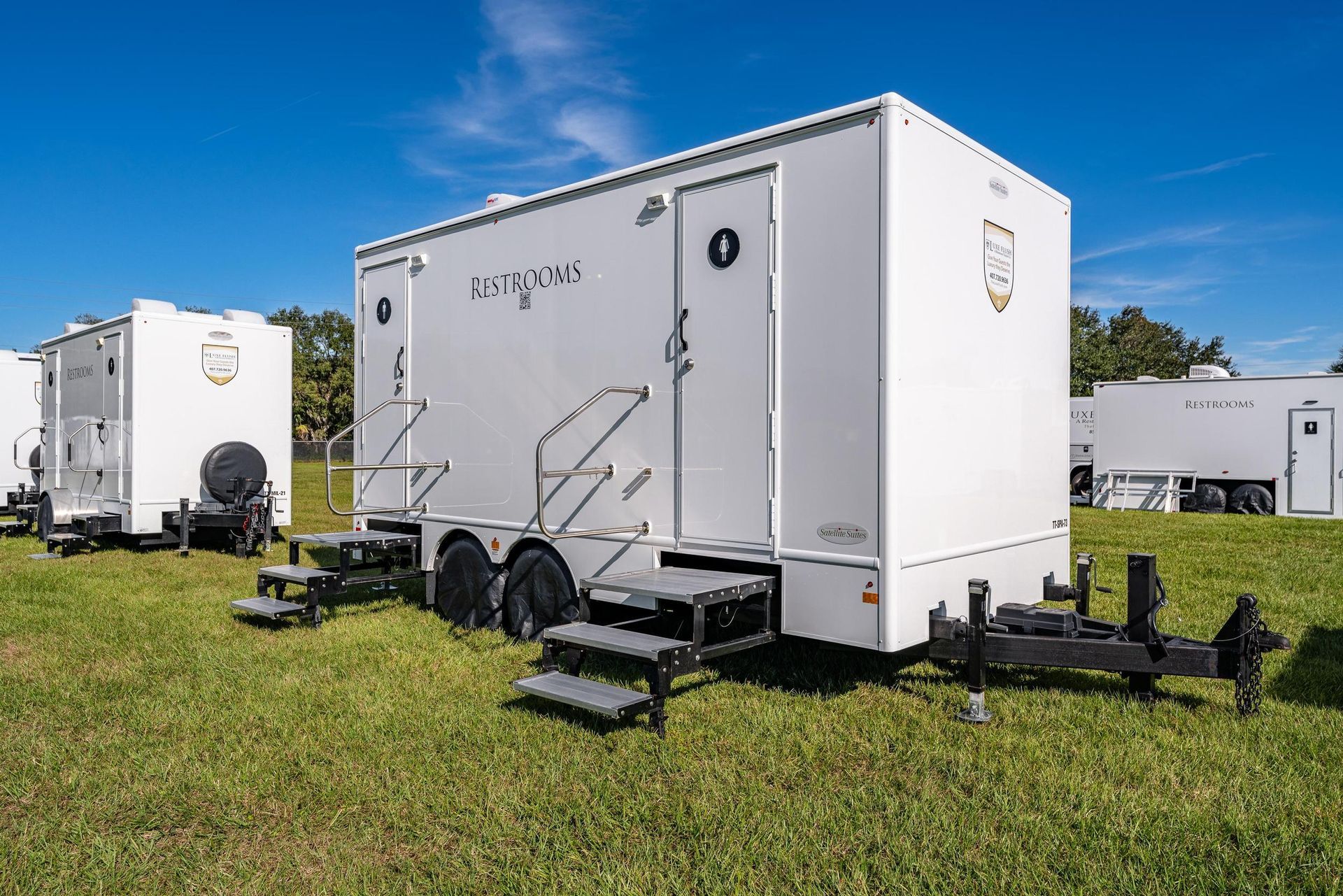 A row of white trailers are parked in a grassy field