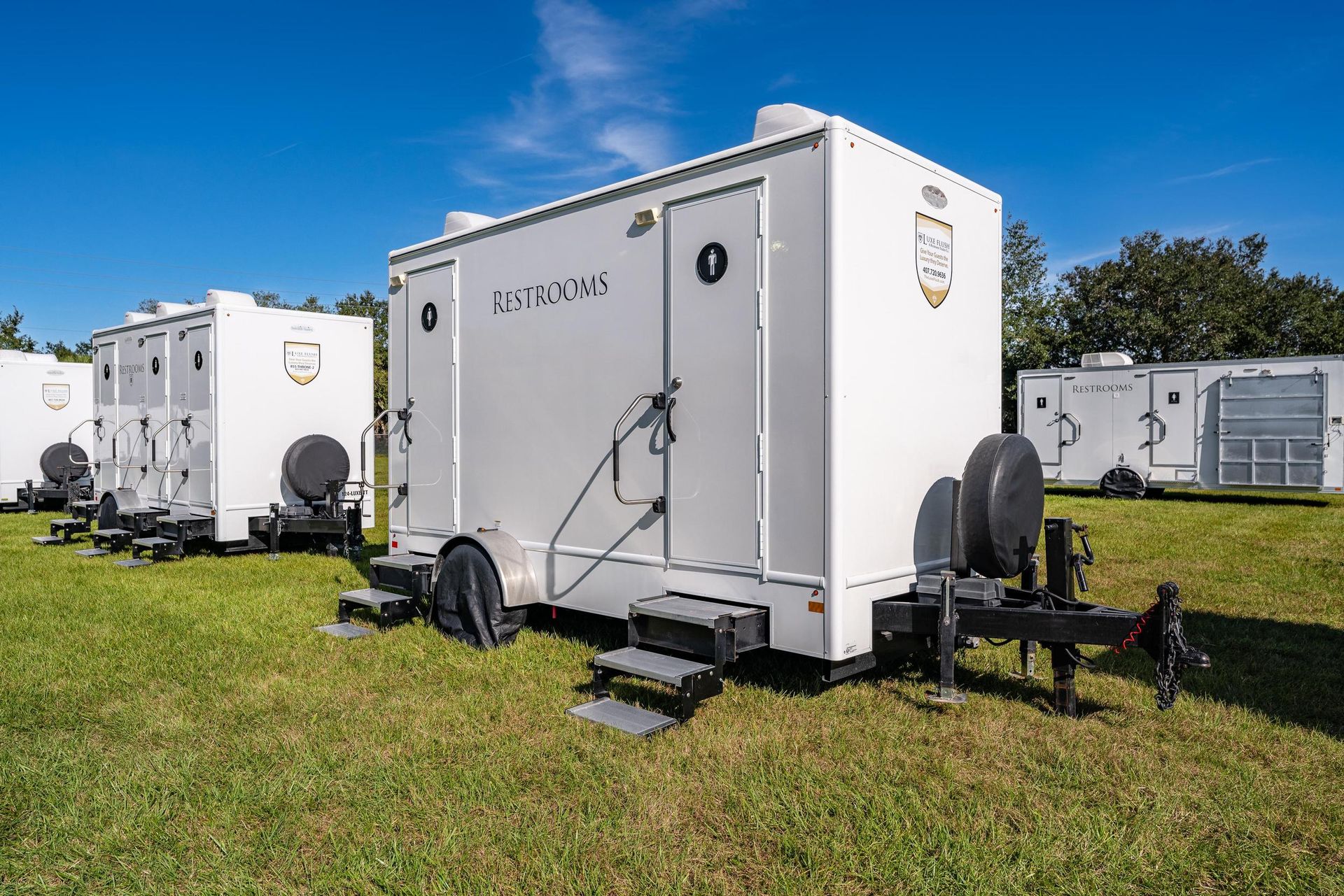 A row of white trailers are parked in a grassy field