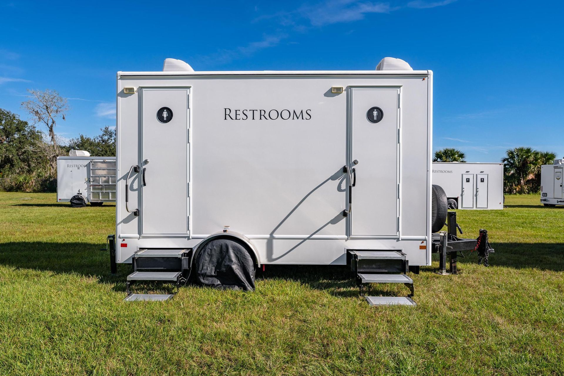 A white trailer is parked in a grassy field