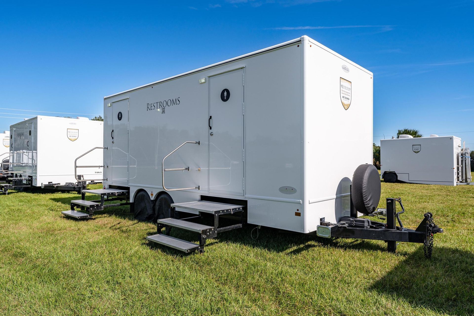 A white trailer is parked in a grassy field