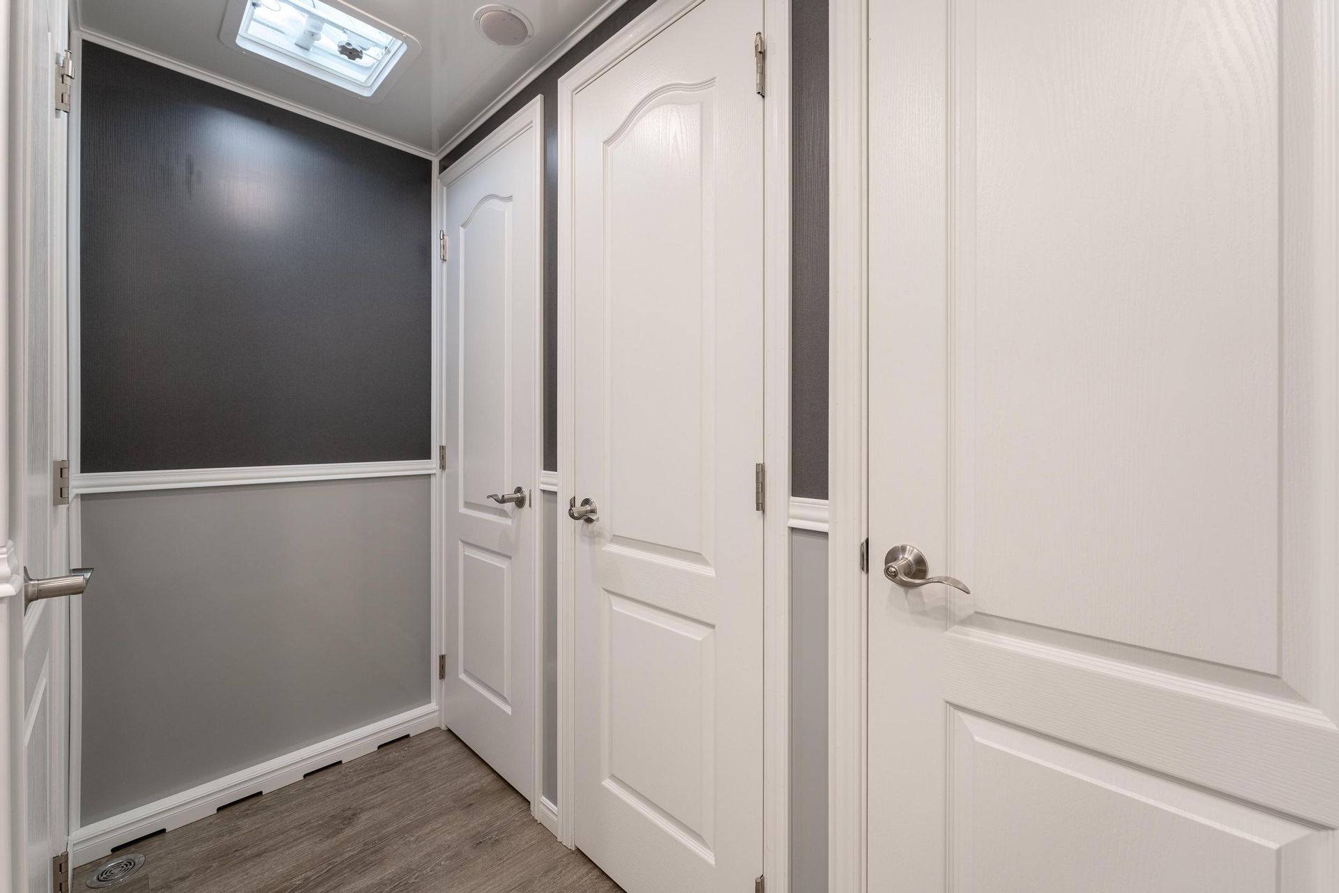 A hallway with a lot of white doors and a black wall