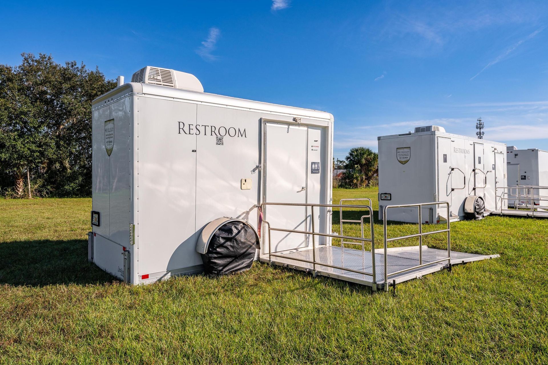 A row of white trailers are parked in a grassy field