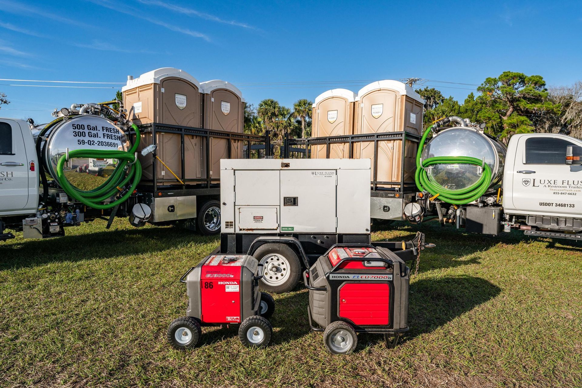 Portable toilets on trucks with a generator and smaller generators on the grass.