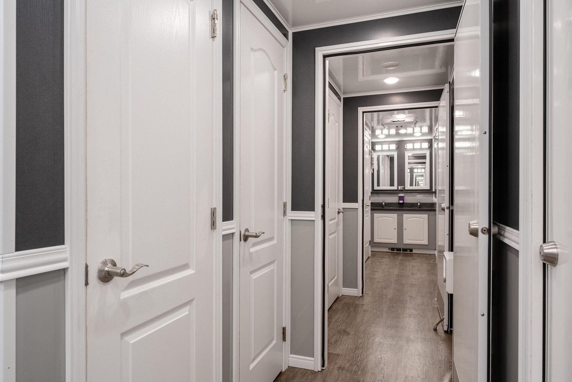 A hallway with white doors leading to a bathroom
