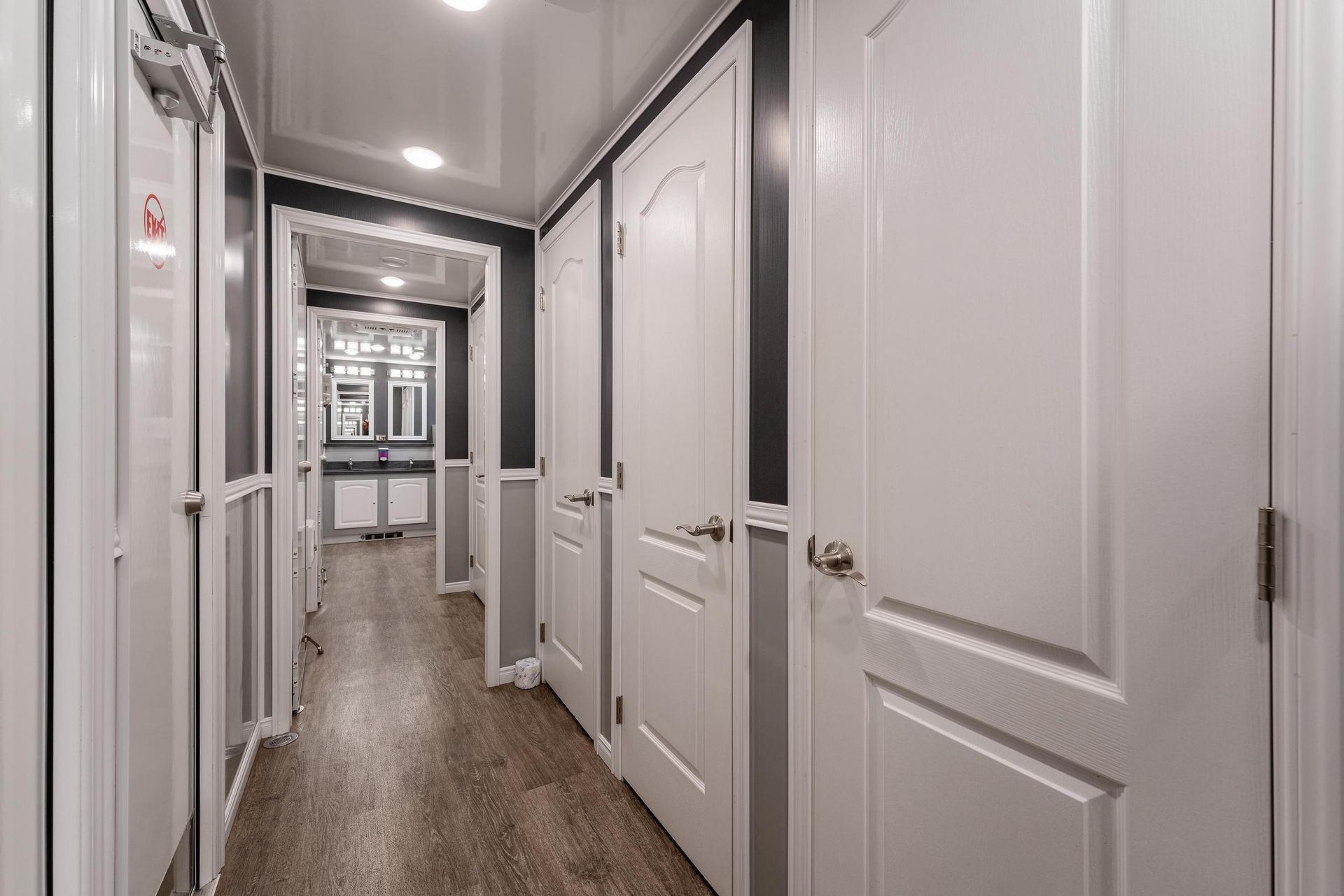 A long hallway with white doors and wooden floors in a house
