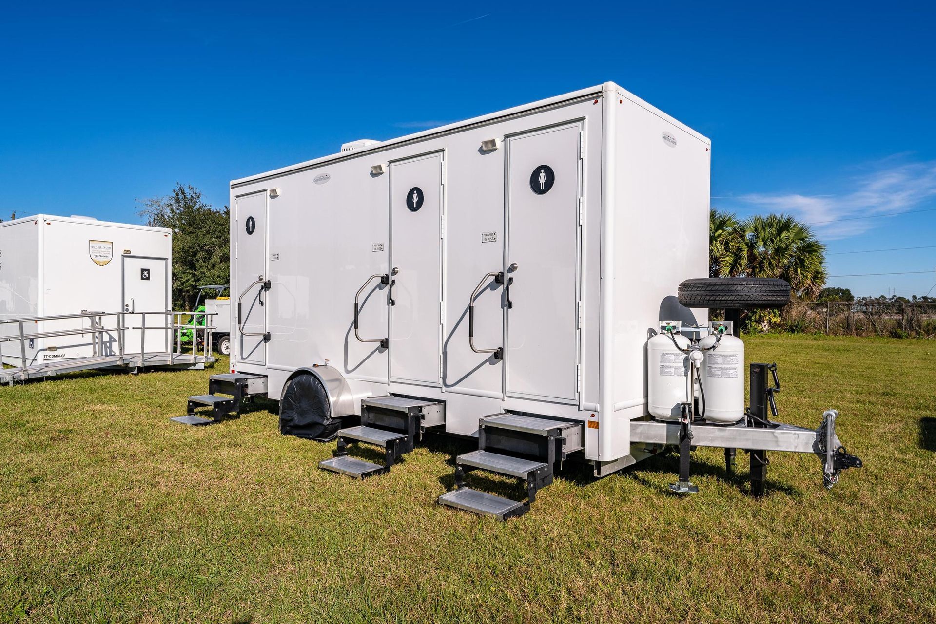 A row of white trailers are parked in a grassy field