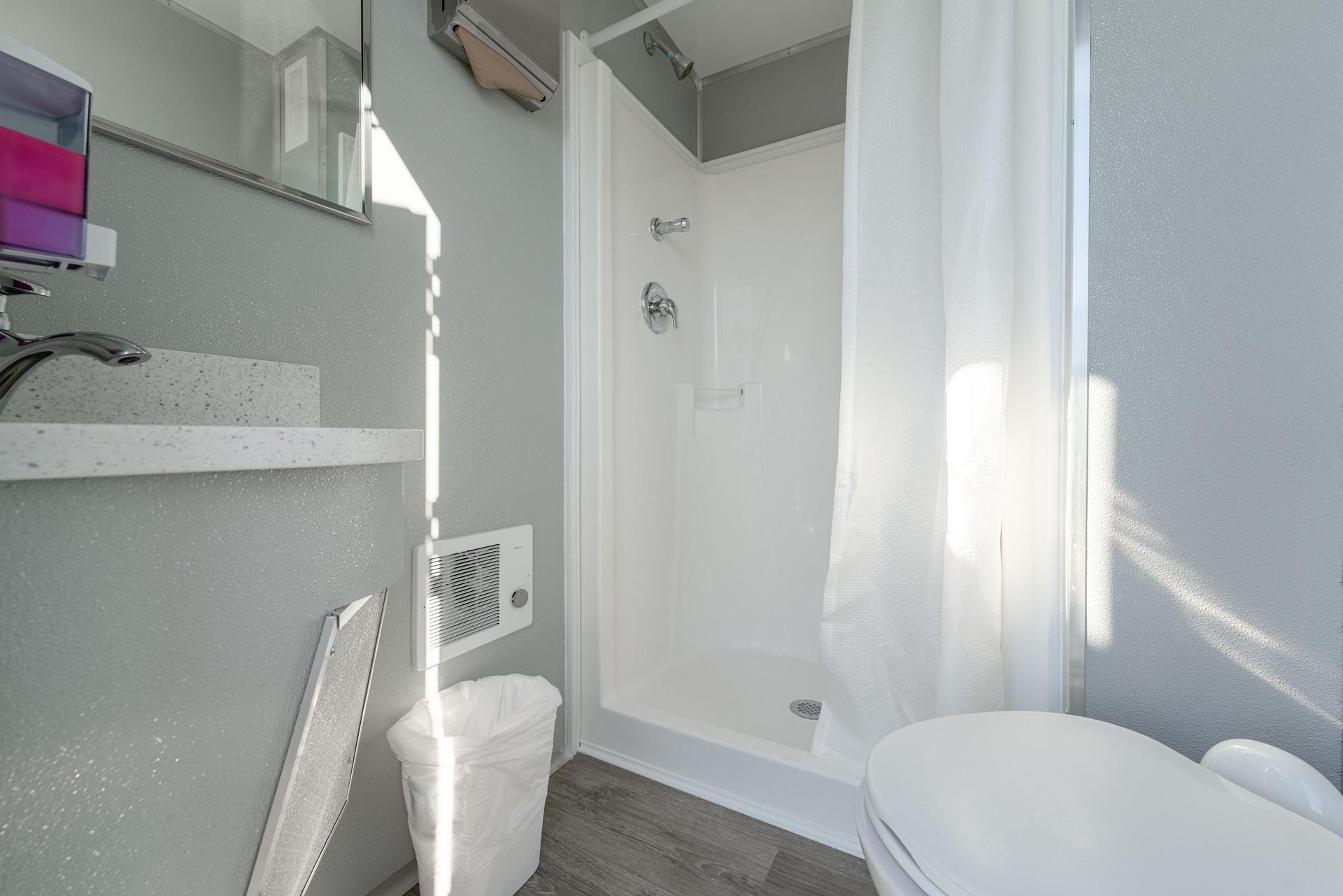 A bathroom with a toilet, sink, shower, and mirror