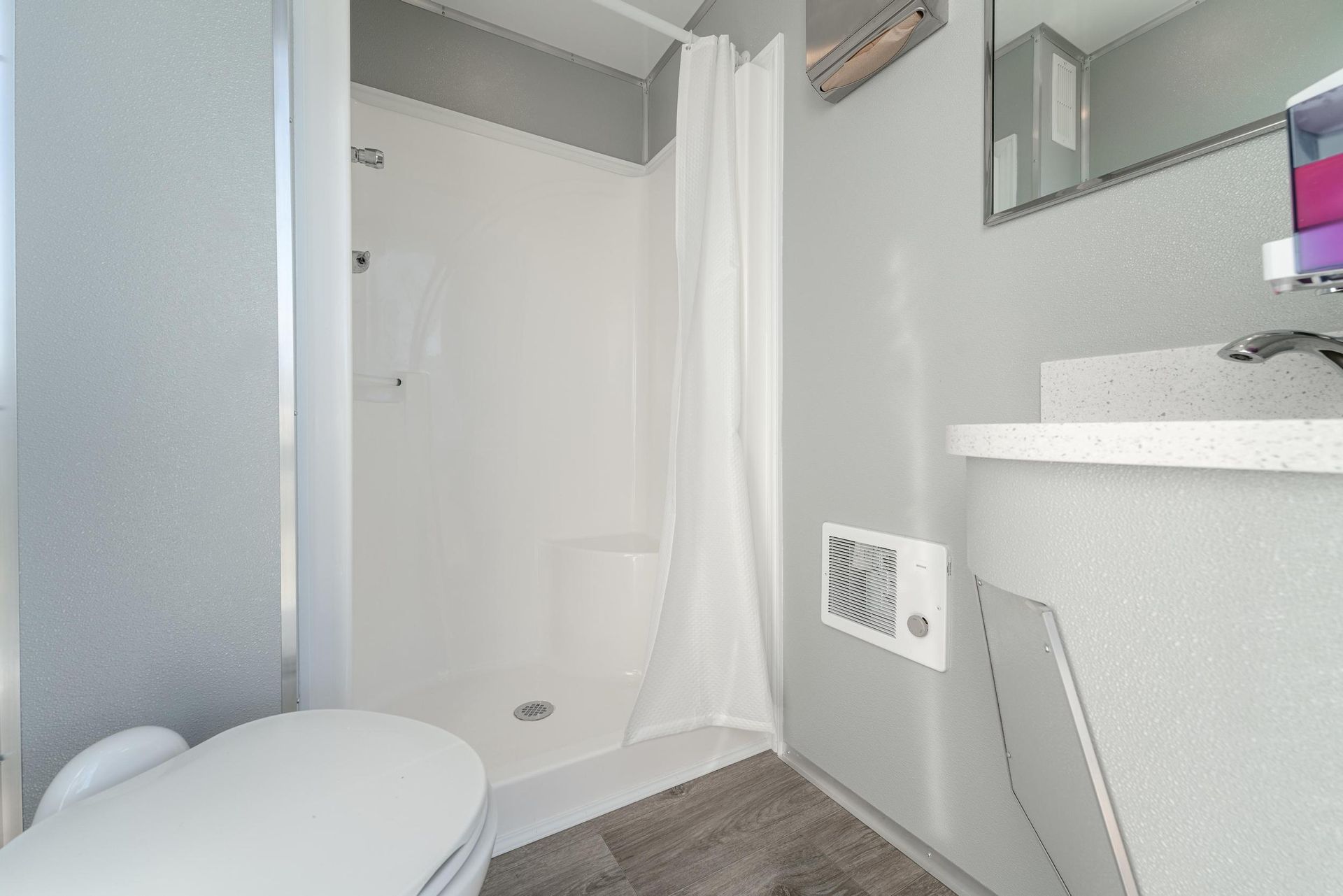 A bathroom with a toilet, sink, shower, and mirror