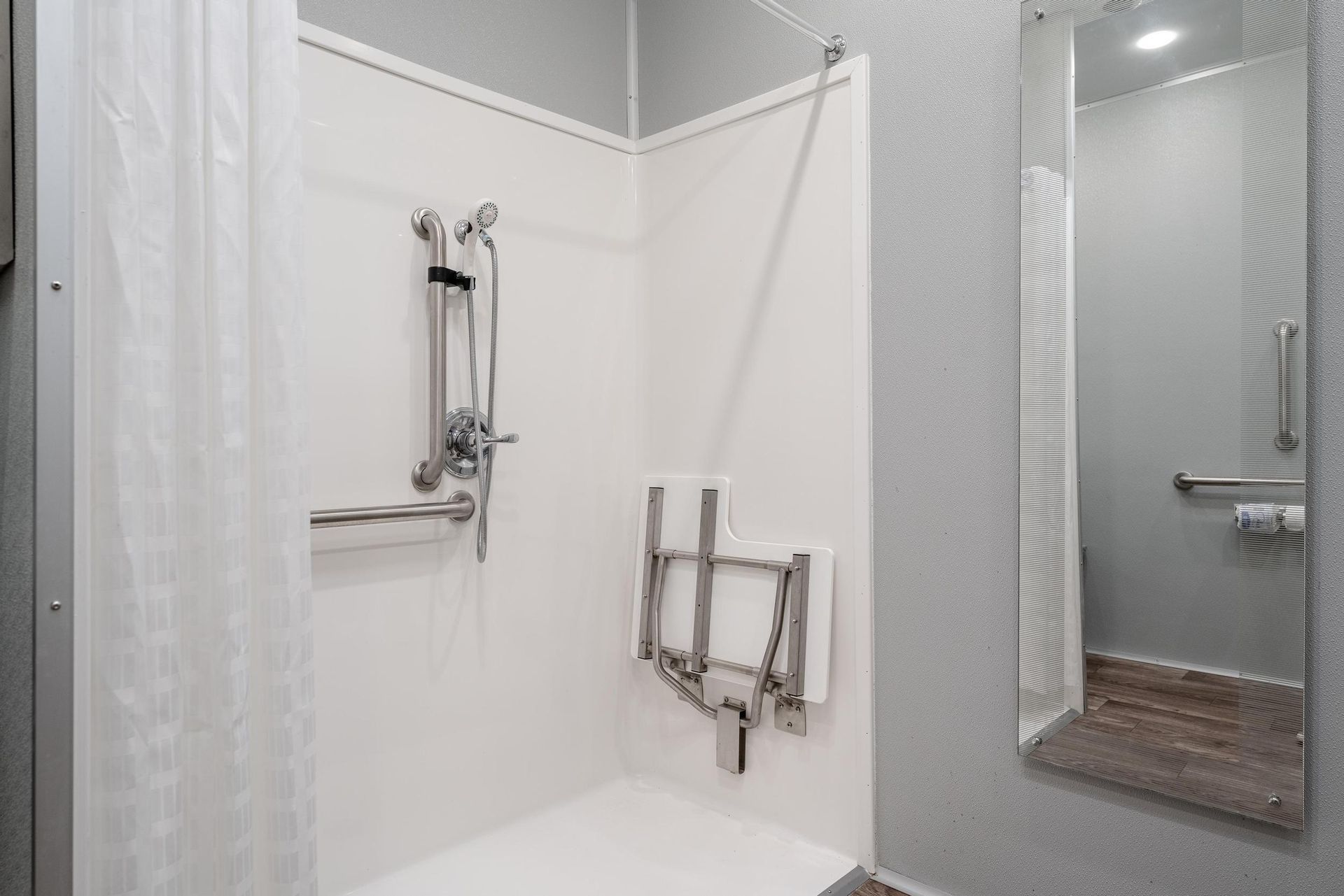 A bathroom with a handicapped shower and a mirror