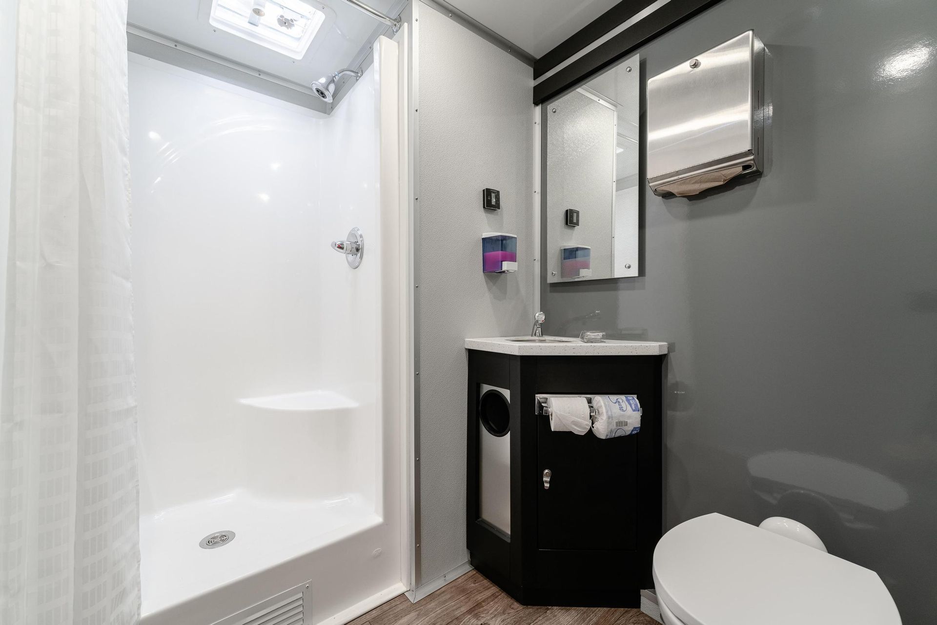 A bathroom with a toilet, sink, shower, and mirror