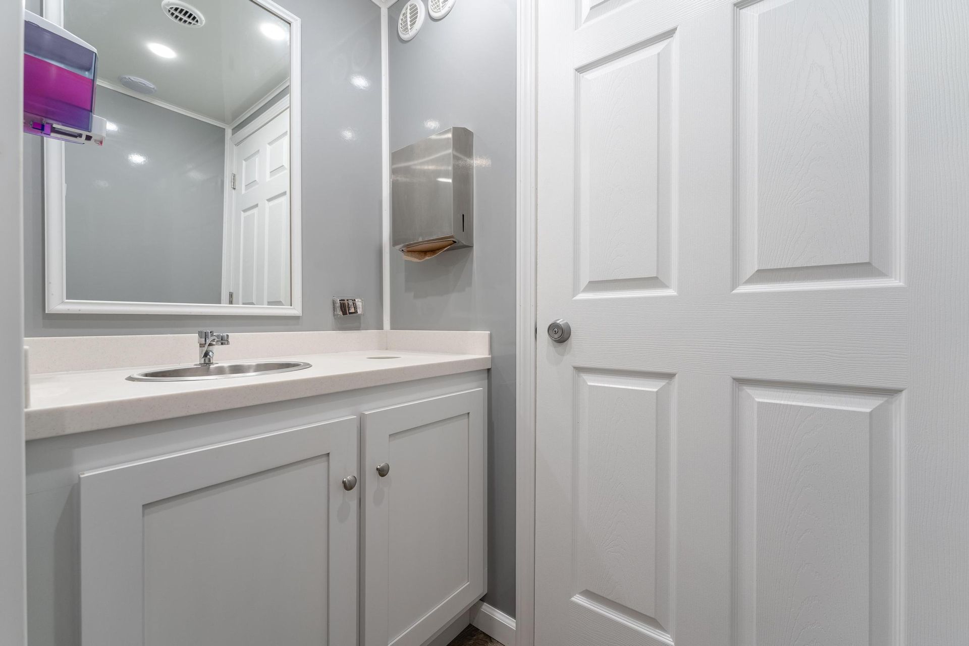 A bathroom with a sink, mirror, and door