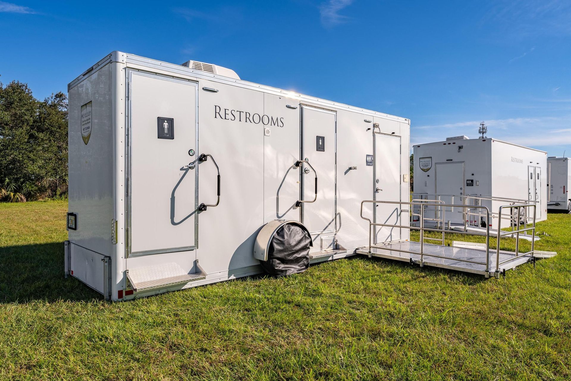 A row of white trailers are parked in a grassy field