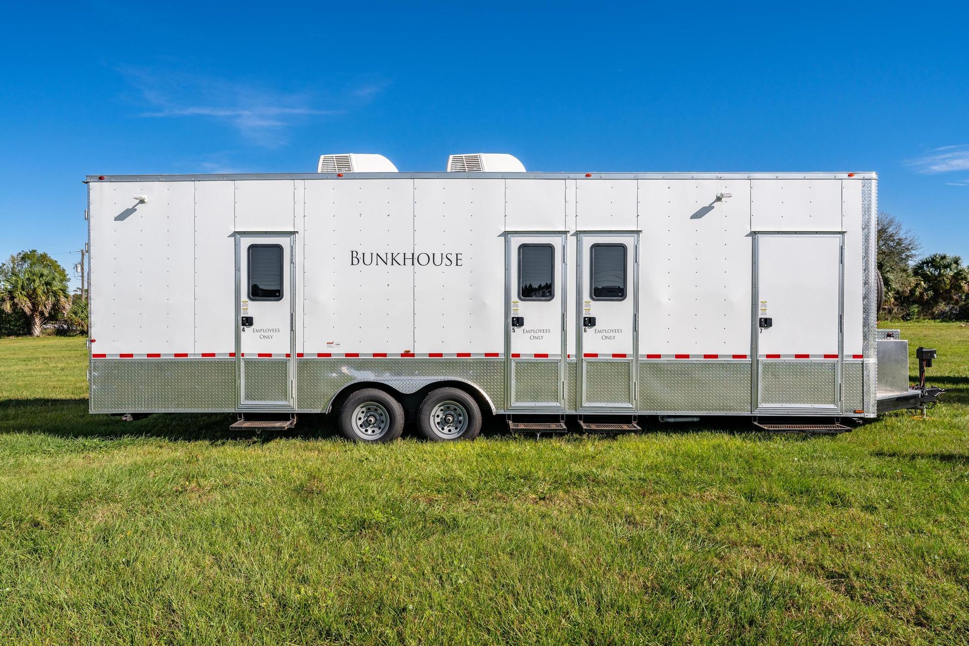 A white trailer is parked in a grassy field