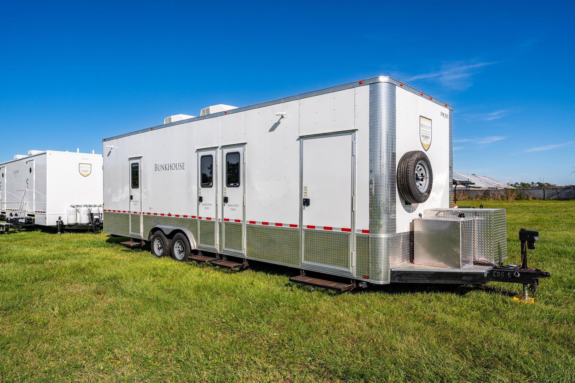 A white trailer is parked in a grassy field